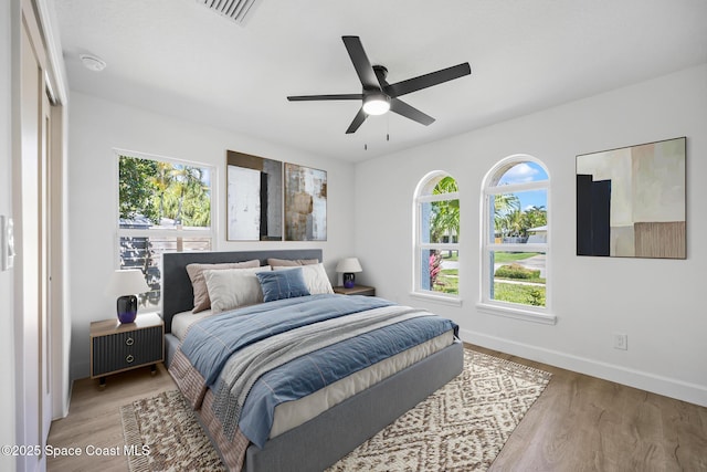 bedroom with light wood-style floors, baseboards, and ceiling fan
