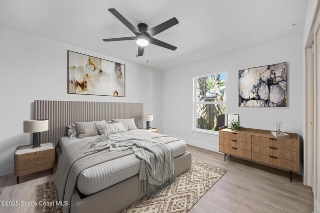 bedroom with light wood finished floors, baseboards, and ceiling fan