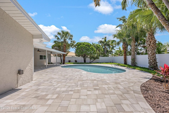 view of pool with ceiling fan, a fenced backyard, and a patio