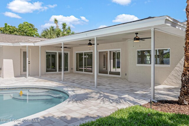 rear view of property featuring ceiling fan, stucco siding, an outdoor pool, and a patio area