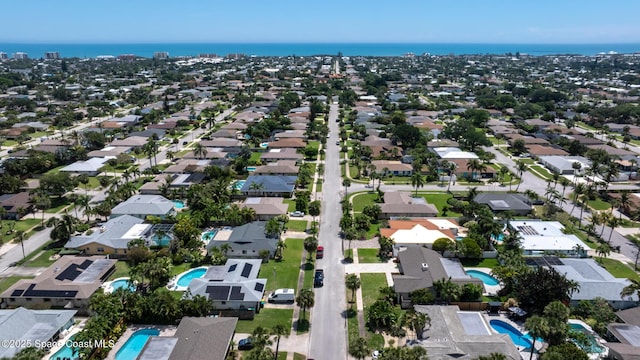 aerial view of property and surrounding area with a pool area, a large body of water, and nearby suburban area
