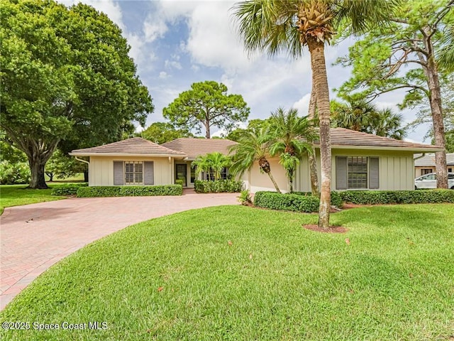 single story home with decorative driveway, a front lawn, and an attached garage