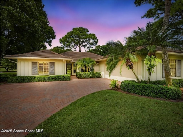 ranch-style house featuring decorative driveway, a tile roof, and a front yard