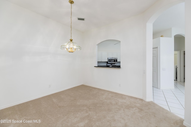 7433 Monterey Ct, Melbourne, FL 32940 - empty room featuring light colored carpet, arched walkways, a chandelier, baseboards, and light tile patterned floors