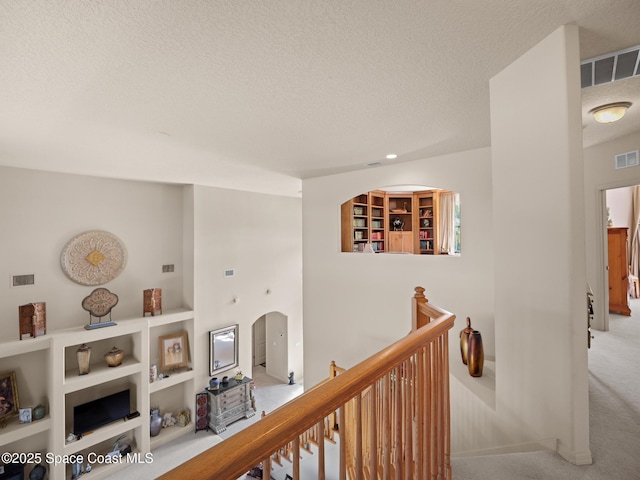 1013 Balmoral Way, Melbourne, FL 32940 - hall with an upstairs landing, a textured ceiling, carpet floors, and arched walkways