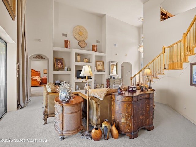1013 Balmoral Way, Melbourne, FL 32940 - living room featuring carpet flooring, a high ceiling, arched walkways, built in shelves, and stairway