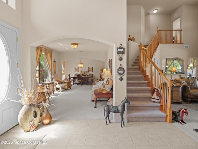 1013 Balmoral Way, Melbourne, FL 32940 - carpeted foyer featuring arched walkways, a towering ceiling, stairs, and tile patterned flooring
