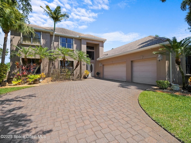 1013 Balmoral Way, Melbourne, FL 32940 - view of front facade featuring a tiled roof, decorative driveway, stucco siding, and a garage