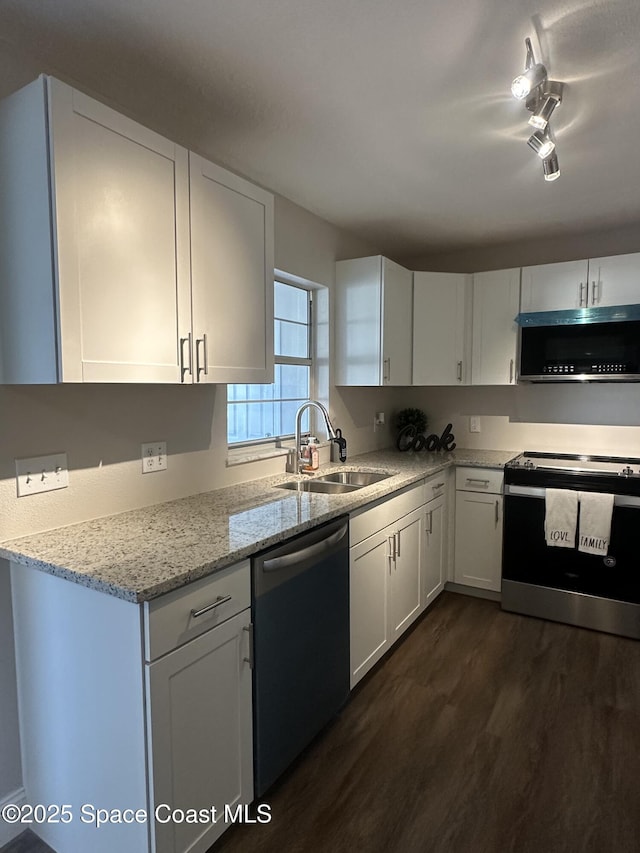 kitchen with stainless steel appliances, dark wood-type flooring, a sink, light stone countertops, and white cabinetry
