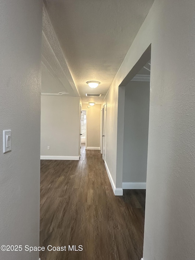 corridor featuring baseboards and dark wood-style floors