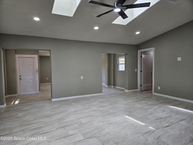 unfurnished living room featuring a skylight, a ceiling fan, recessed lighting, lofted ceiling, and baseboards