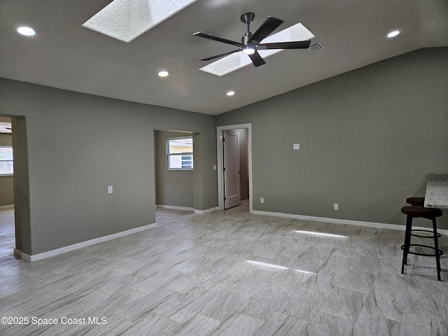 spare room featuring a skylight, lofted ceiling, recessed lighting, a ceiling fan, and baseboards