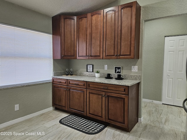 kitchen with a textured wall and baseboards