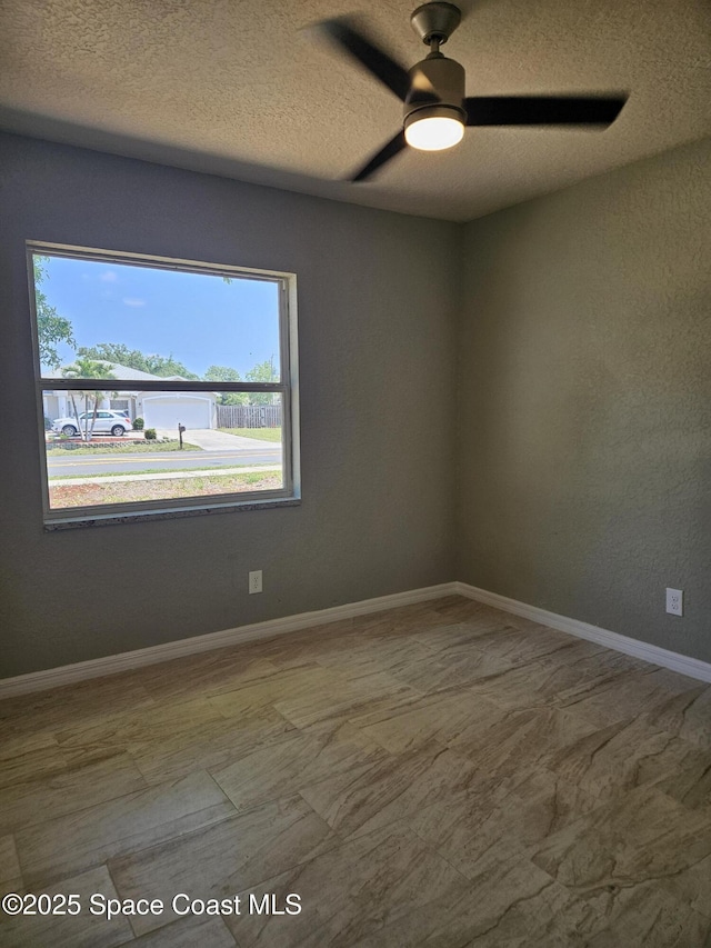 empty room featuring healthy amount of natural light, a textured ceiling, ceiling fan, and baseboards