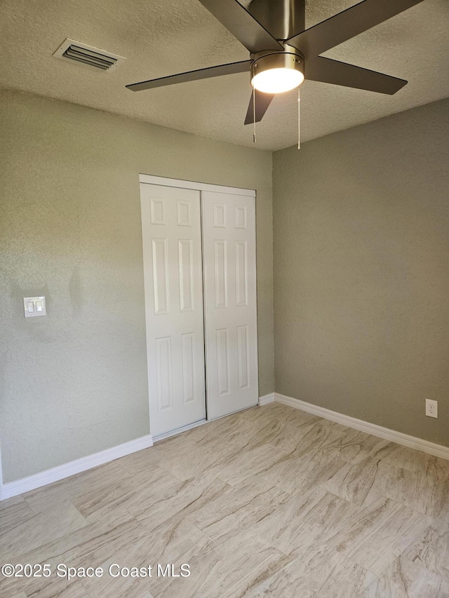 unfurnished bedroom featuring a closet, baseboards, a ceiling fan, and a textured ceiling