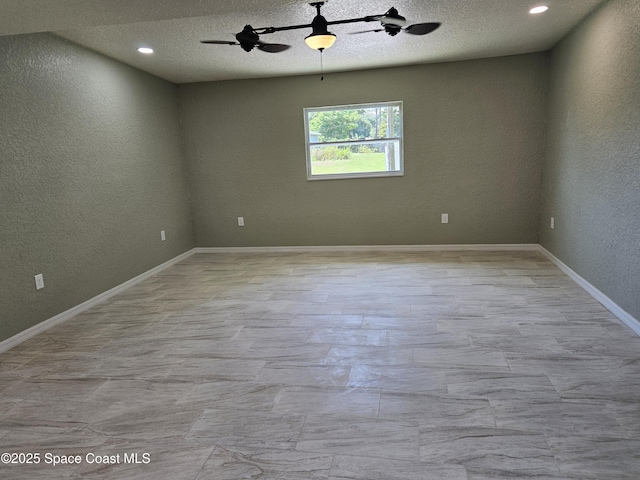 unfurnished room with a textured wall, a ceiling fan, baseboards, and a textured ceiling