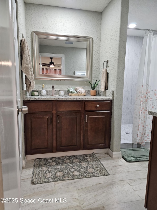bathroom featuring a shower with shower curtain, vanity, and a textured wall