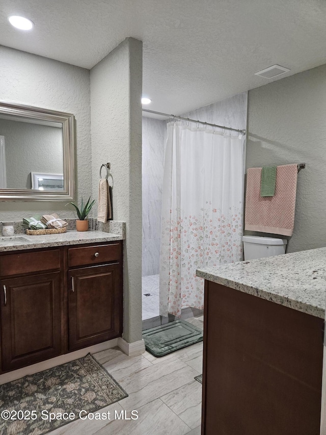 full bathroom featuring toilet, a shower with curtain, vanity, a textured wall, and a textured ceiling