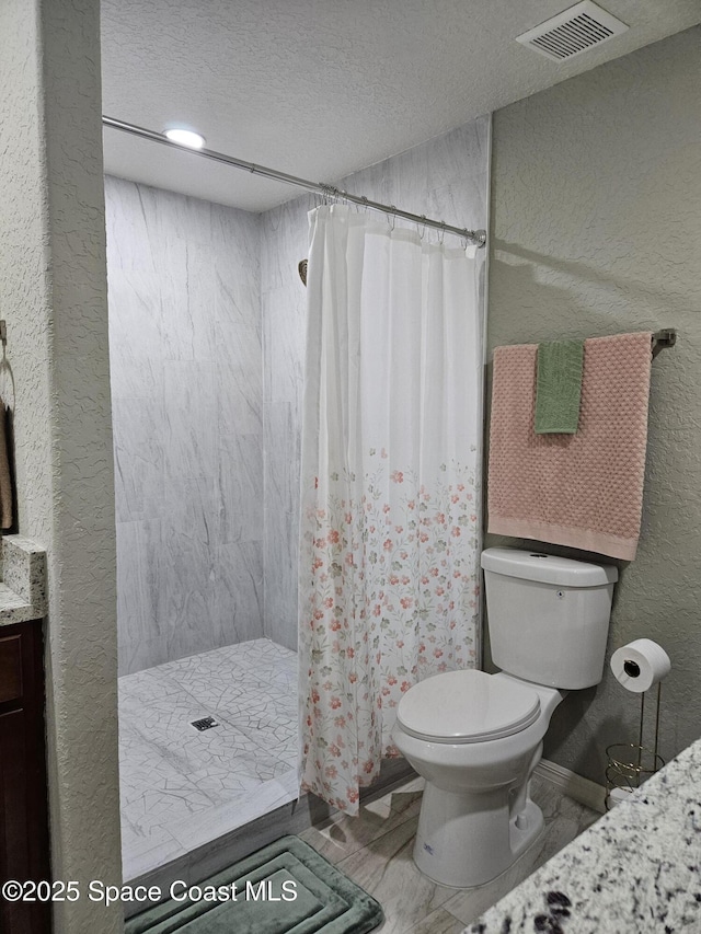 full bath with toilet, a stall shower, a textured wall, a textured ceiling, and vanity