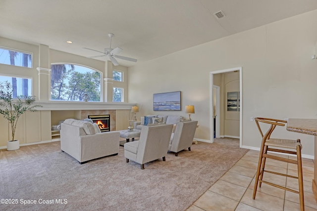 living area featuring plenty of natural light, light colored carpet, a tile fireplace, and a ceiling fan