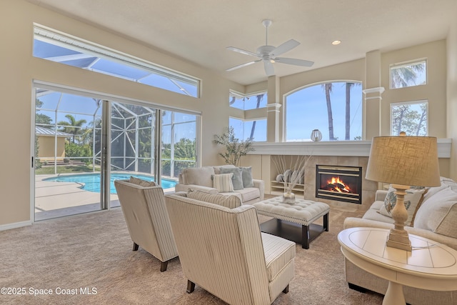 living room with a ceiling fan, a sunroom, carpet flooring, a tiled fireplace, and recessed lighting