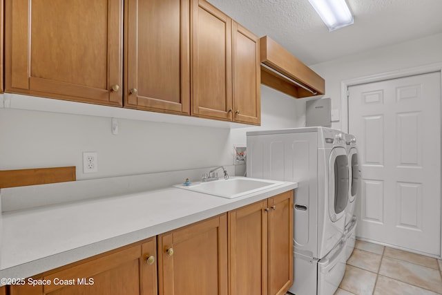 laundry area featuring cabinet space, washing machine and clothes dryer, light tile patterned floors, and a textured ceiling