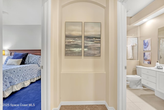 bedroom with connected bathroom and light tile patterned floors