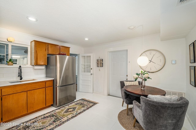 847 W Virginia St, Cocoa, FL 32927 - kitchen featuring freestanding refrigerator, a sink, light countertops, brown cabinetry, and tasteful backsplash