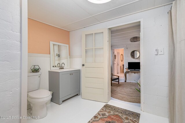 847 W Virginia St, Cocoa, FL 32927 - bathroom featuring vanity, toilet, a wainscoted wall, and tile patterned flooring