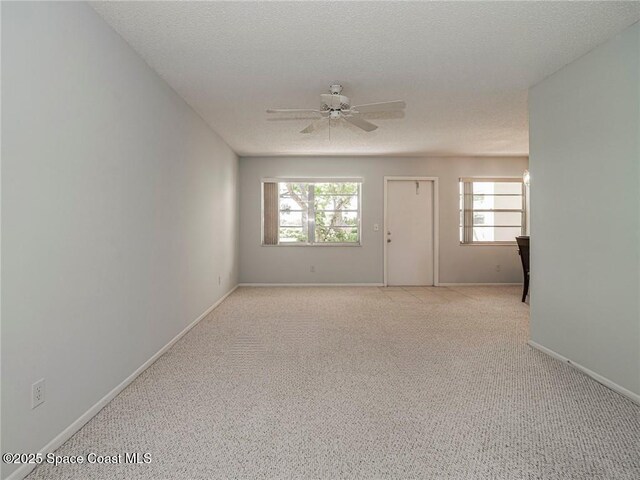 spare room featuring ceiling fan, healthy amount of natural light, light carpet, and baseboards