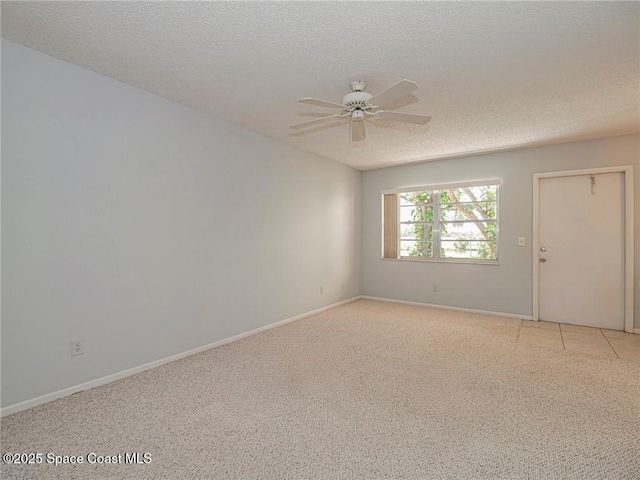spare room with light colored carpet, a ceiling fan, a textured ceiling, and baseboards