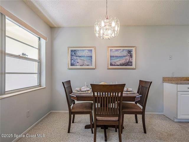 dining space with a textured ceiling, light carpet, a chandelier, and baseboards