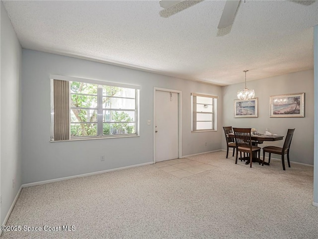 dining space with light colored carpet, a chandelier, ceiling fan, a textured ceiling, and baseboards