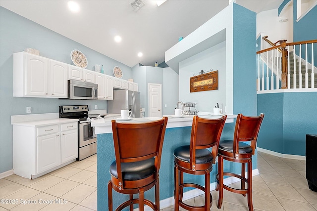 2648 Daulby St, Kissimmee, FL 34747 - kitchen with stainless steel appliances, a kitchen bar, light tile patterned floors, white cabinets, and lofted ceiling