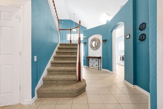 2648 Daulby St, Kissimmee, FL 34747 - stairs with tile patterned floors, arched walkways, a textured wall, baseboards, and healthy amount of natural light