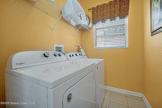 2648 Daulby St, Kissimmee, FL 34747 - clothes washing area featuring washing machine and clothes dryer, light tile patterned floors, baseboards, and a textured wall