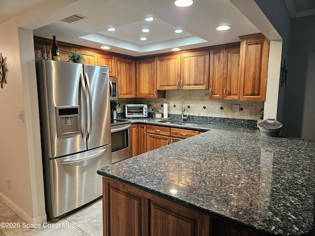 1700 S Atlantic Ave Unit 107, Cocoa Beach, FL 32931 - kitchen with stainless steel appliances, a sink, a raised ceiling, a peninsula, and brown cabinets