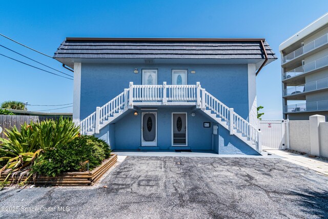 1145 S Atlantic Ave Unit B, Cocoa Beach, FL 32931 - view of front of house featuring stairs, stucco siding, and fence