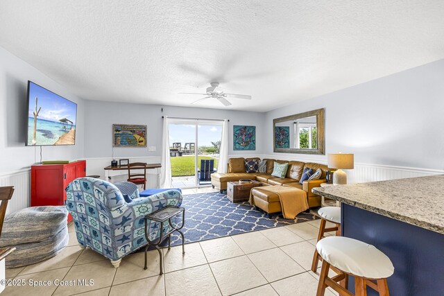 1145 S Atlantic Ave Unit B, Cocoa Beach, FL 32931 - living room featuring a wainscoted wall, light tile patterned flooring, healthy amount of natural light, ceiling fan, and a textured ceiling
