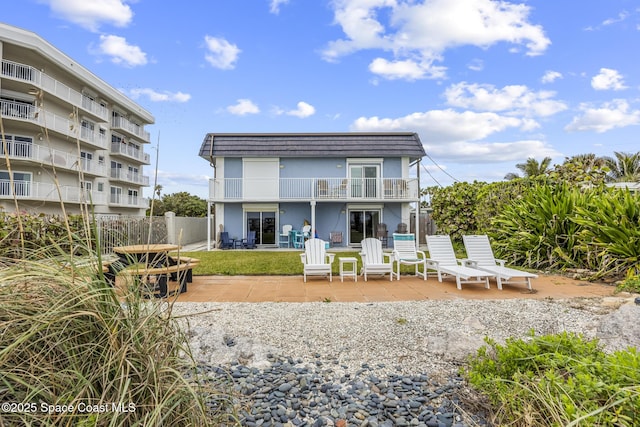 1145 S Atlantic Ave Unit B, Cocoa Beach, FL 32931 - rear view of house featuring a balcony, a patio, fence, mansard roof, and stucco siding