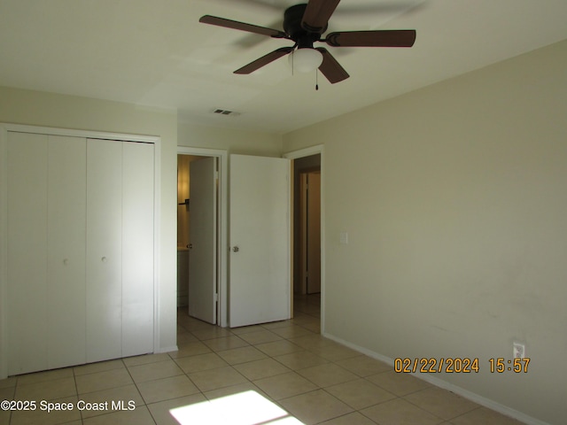 unfurnished bedroom with a closet, light tile patterned floors, baseboards, and a ceiling fan
