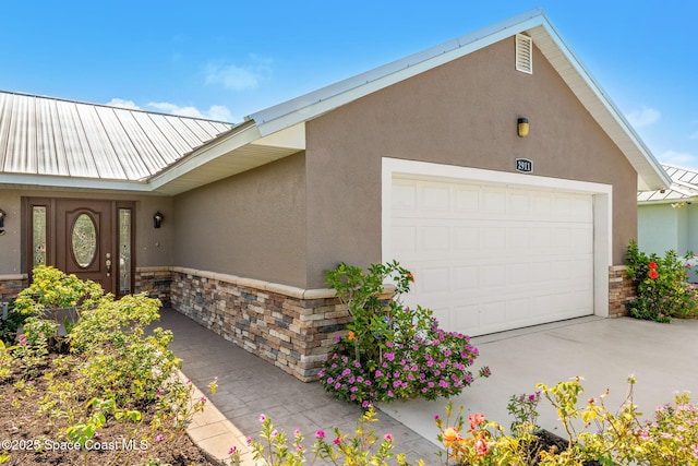 view of front of home with stone siding, stucco siding, metal roof, and an attached garage