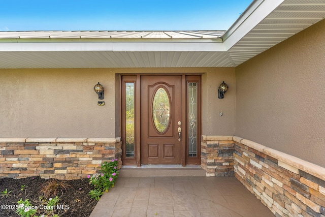 doorway to property featuring stucco siding and stone siding