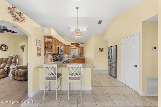 kitchen featuring appliances with stainless steel finishes, open shelves, a peninsula, open floor plan, and a kitchen breakfast bar
