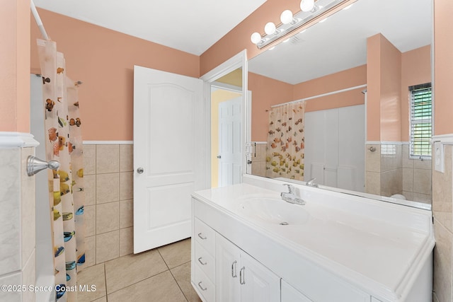 full bath featuring tile walls, a wainscoted wall, tile patterned flooring, a shower with curtain, and vanity