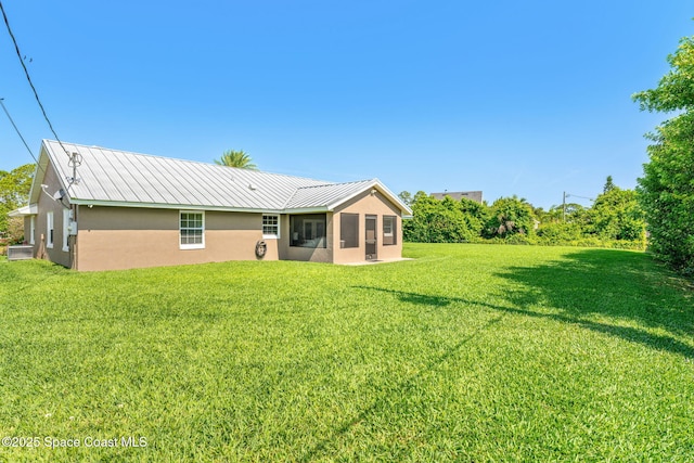 rear view of property featuring stucco siding, a sunroom, a yard, metal roof, and cooling unit