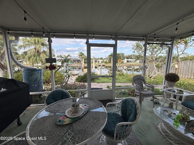 sunroom with track lighting, a water view, and healthy amount of natural light
