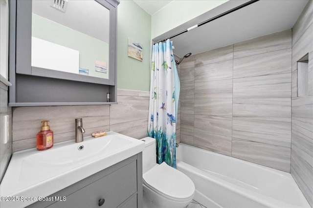 bathroom featuring toilet, tile walls, shower / bathtub combination with curtain, and vanity