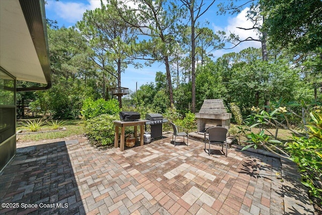 view of patio / terrace with an outdoor stone fireplace and a grill