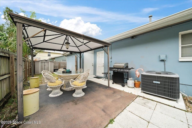 view of patio featuring a gazebo, central AC unit, a storage shed, outdoor dining space, and an outbuilding